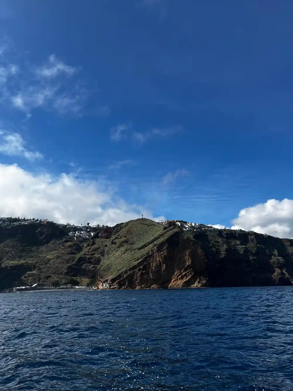 a steep green volcanic headland dropping straight into the sea